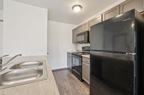Omaha townhouse for rent - A black refrigerator is in the corner of a kitchen with a sink and microwave above it.
