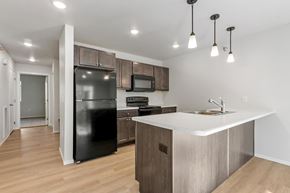 Sioux Falls apartment for rent - A kitchen with a black fridge, microwave, and stove top oven.