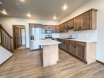 Sioux Falls townhouse for rent - a kitchen with wooden cabinets and stainless steel appliances and a white counter top