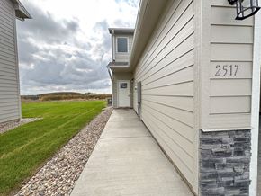 Sioux Falls townhouse for rent - the walkway to the front door of a white house with a grassy field