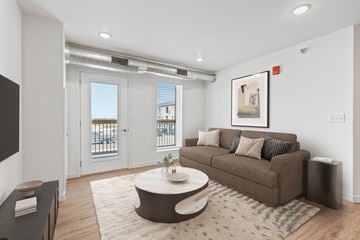 Rapid City apartment for rent - A living room with a brown couch, a coffee table, and a painting on the wall.