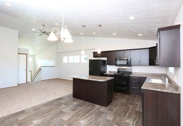 Sioux Falls apartment for rent - an open kitchen and living room with dark wood cabinets and white walls