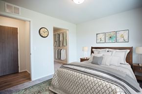 Rapid City apartment for rent - A bedroom with a large bed and a clock on the wall.
