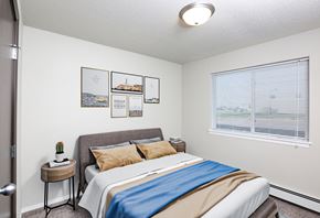 Sioux Falls apartment for rent - A bedroom with a bed, pillows, a small table, and pictures on the wall.
