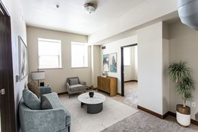 Sioux Falls apartment for rent - A living room with a grey couch, a white coffee table, and a plant.