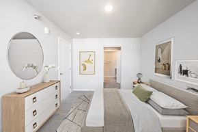 Mitchell apartment for rent - A bedroom with a bed, dresser, mirror, and artwork.