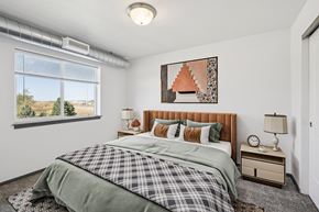 Omaha townhouse for rent - A bedroom with a large bed and a window overlooking a landscape.