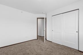 Rapid City townhouse for rent - a bedroom with white walls and carpet and a door to a closet