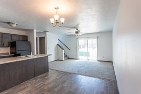 Sioux Falls townhouse for rent - an empty living room with a kitchen and a ceiling fan