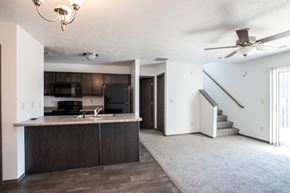 Sioux Falls townhouse for rent - an empty living room with a kitchen and a ceiling fan