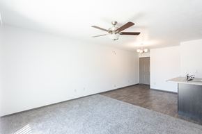 Sioux Falls townhouse for rent - an empty living room with a ceiling fan and a kitchen