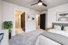 Sioux Falls apartment for rent - A bedroom with a bed, a ceiling fan, and a painting on the wall.