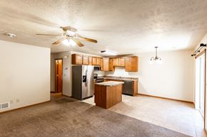 Sioux Falls townhouse for rent - an empty living room with a kitchen and a ceiling fan