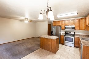 Sioux Falls townhouse for rent - an empty kitchen with wooden cabinets and stainless steel appliances