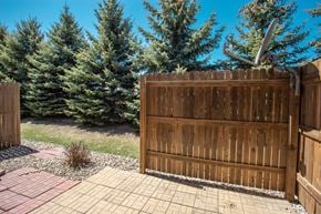 Sioux Falls townhouse for rent - a wooden fence in front of a yard with pine trees