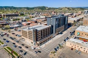 Rapid City apartment for rent - A city street with cars and buildings.
