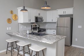 Sioux Falls apartment for rent - a kitchen with white cabinets and a counter top with stools