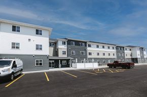 Mitchell apartment for rent - A parking lot with a white van and a red truck parked in front of a building.