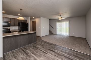 Grimes townhouse for rent - A spacious kitchen with dark wood cabinets and a black refrigerator.