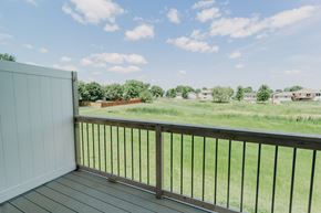 Tea apartment for rent - a balcony with a view of a grassy field and houses in the background