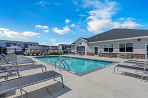 Sioux Falls townhouse for rent - A swimming pool surrounded by sun loungers and a building in the background.