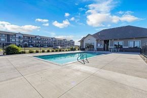 Sioux Falls townhouse for rent - A swimming pool in a concrete pool area with a building in the background.