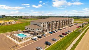 Sioux Falls apartment for rent - A large apartment complex with a pool and cars parked in the parking lot.