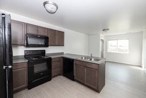 Sioux Falls apartment for rent - an empty kitchen with dark wood cabinets and black appliances and a sink