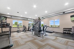 Sioux Falls apartment for rent - A spacious gym with a variety of equipment and a view of the outdoors through the windows.