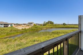 Sioux Falls apartment for rent - A wooden deck overlooks a grassy field with a river and houses in the distance.