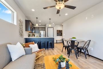 Brandon townhouse for rent - A modern living room with a grey couch, a wooden coffee table, and a dining table with chairs.