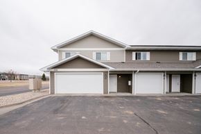 Mitchell townhouse for rent - A two-story house with a garage is situated in a parking lot.