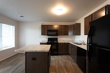 Sioux Falls apartment for rent - a kitchen with dark wood cabinets and granite counter tops and black appliances