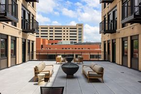 Des Moines apartment for rent - A patio with chairs and a table is surrounded by buildings.