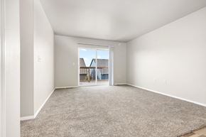 Sioux Falls apartment for rent - A spacious room with a carpeted floor and a sliding glass door leading to a balcony.