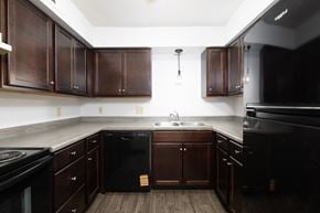 Sioux Falls apartment for rent - A kitchen with dark wood cabinets and black appliances.