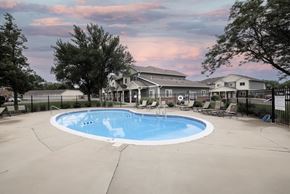 Sioux Falls apartment for rent - A large outdoor swimming pool surrounded by a fence and a house in the background.