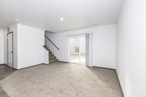 Sioux Falls townhouse for rent - A spacious, empty room with a staircase and a carpeted floor.
