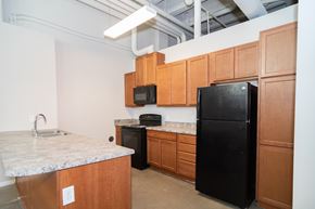Sioux City apartment for rent - A kitchen with black appliances and wooden cabinets.