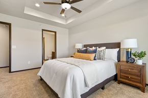 Brandon townhouse for rent - A bedroom with a large bed, a ceiling fan, and a nightstand with a plant on it.