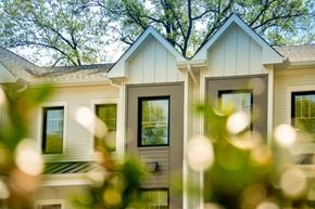 Madison apartment for rent - A house with a white facade and a large window is surrounded by greenery.
