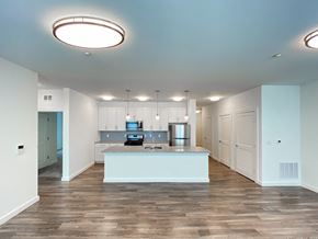 Jersey City apartment for rent - an empty living room with a kitchen with white cabinets and a counter top