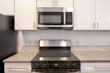 Madison apartment for rent - A modern kitchen with a stove top oven and microwave above it.