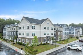 South Brunswick apartment for rent - A large building with a grey roof and white walls with windows.
