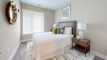 Princeton apartment for rent - A bedroom with a large bed, a nightstand, and a mirror on the wall.