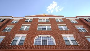 Orange apartment for rent - a red brick building with windows and a blue sky