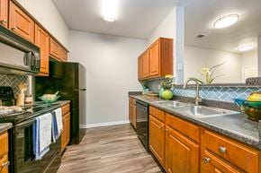 Universal City apartment for rent - a kitchen with black appliances and wood cabinets at Sunrise Canyon, Universal City, TX