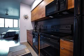 San Antonio apartment for rent - Contemporary kitchen with black appliances and wood finishes at THE'68 Apartments, San Antonio