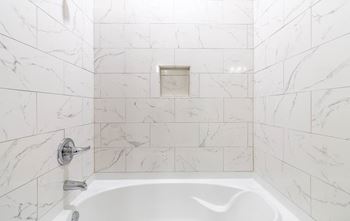 A white tiled bathroom with a tub and a sink