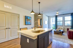 Austin apartment for rent - a kitchen with an island and a living room with a couch at Birdie on Woodland Greens, Texas 78726